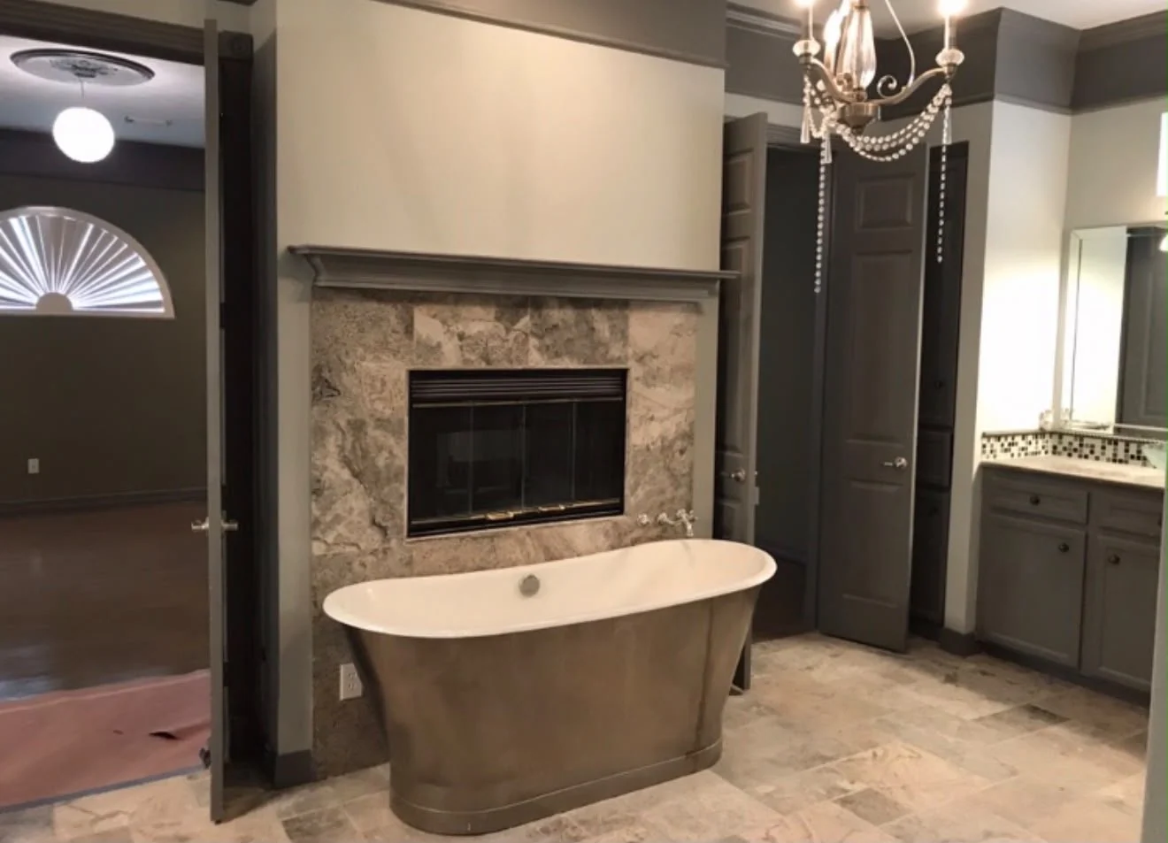 Primary bathroom by LL General Contractor with a freestanding tub beside a tiled fireplace
