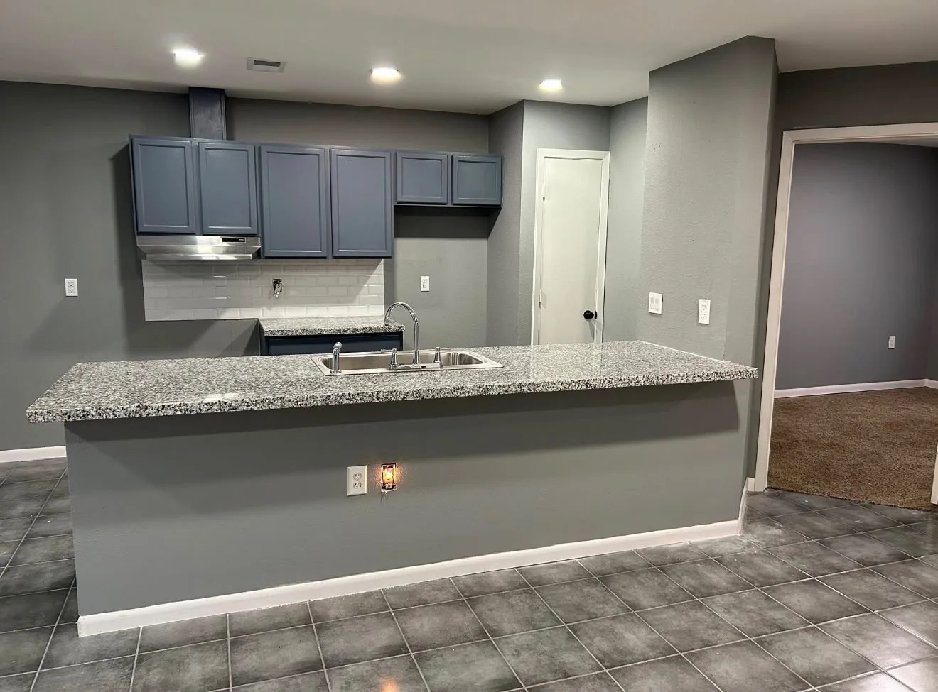 A Houston kitchen rebuilt with blue gray cabinets, granite counters and a subway tile backsplash after the remodel